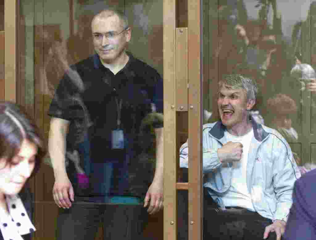 Former Yukos CEO Mikhail Khodorkovsky (left) and his co-defendant Platon Lebedev stand behind a glass wall at a court in Moscow, on May 24. An appeals court upheld the second conviction of Khodorkovsky, but it also reduced his prison sentence by one year. Photo by Iliya Pitalev for RIA Novosti