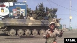 A disabled man begging for help in a Gori street while a Russian tank drives by, 17 August, 2008.