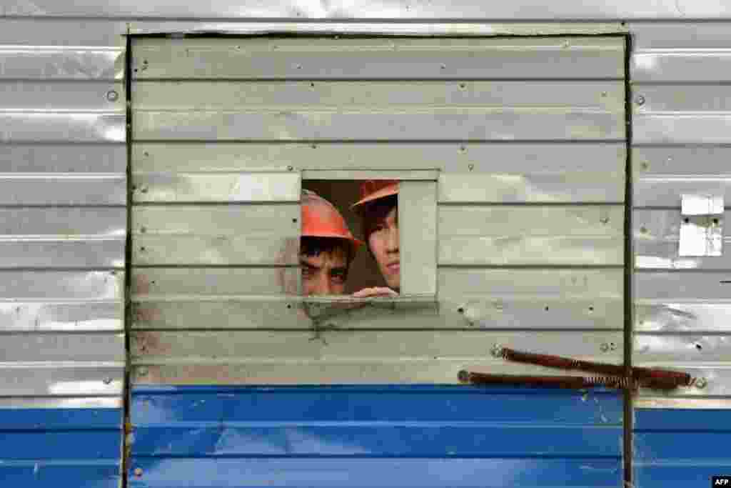 Migrant workers look through a door opening at a Moscow construction site to watch a Russian Orthodox religious procession in May 2013. 