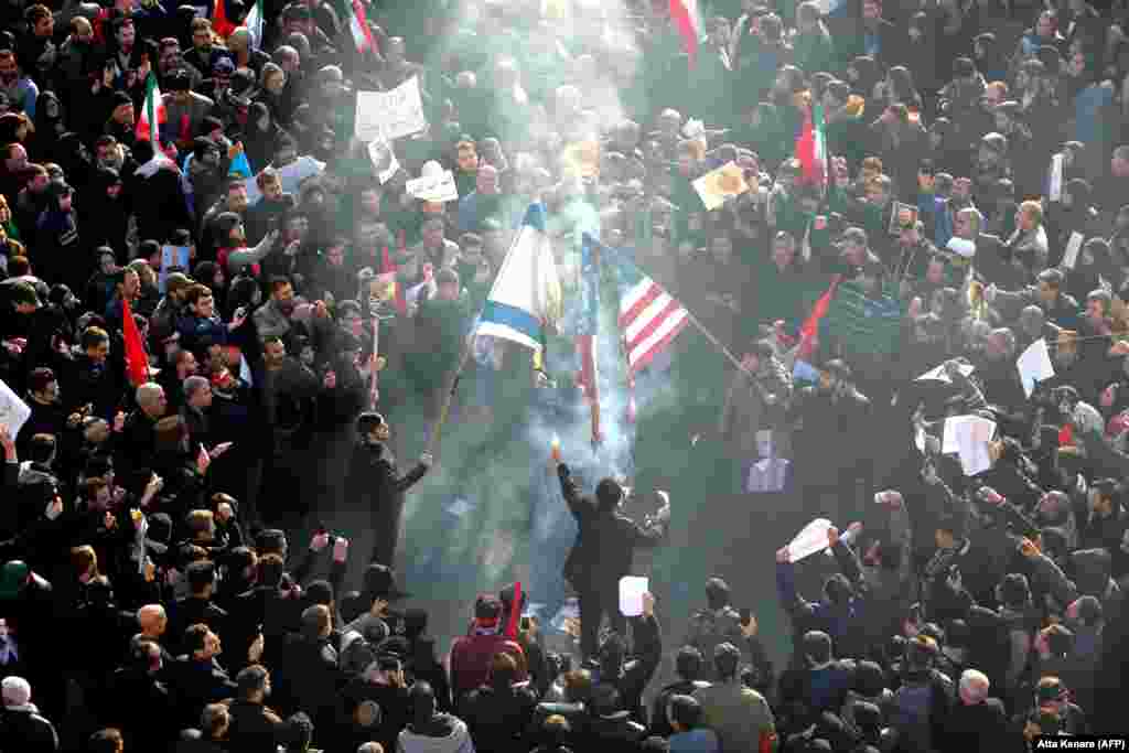 Mourners set a U.S. and an Israeli flag on fire during a funeral procession.