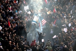 Iranians set a U.S. and an Israeli flag on fire during a funeral procession organised to mourn the slain military commander Qasem Soleimani in Tehran on January 6.