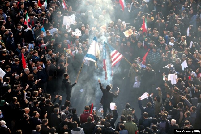 Iranians set a U.S. and an Israeli flag on fire during a funeral procession organised to mourn the slain military commander Qasem Soleimani in Tehran on January 6.