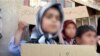 A child without citizenship In Iran holds a placard saying "I don't have an ID". Undated