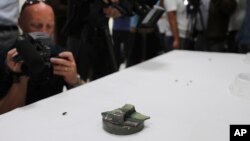 Journalists take pictures of a magnet the U.S. Navy says came from a limpet mine that didn't explode on a Japanese-owned oil tanker at a 5th Fleet base, during a trip organized by the Navy for journalists, near Fujairah, United Arab Emirates, Wednesday, J