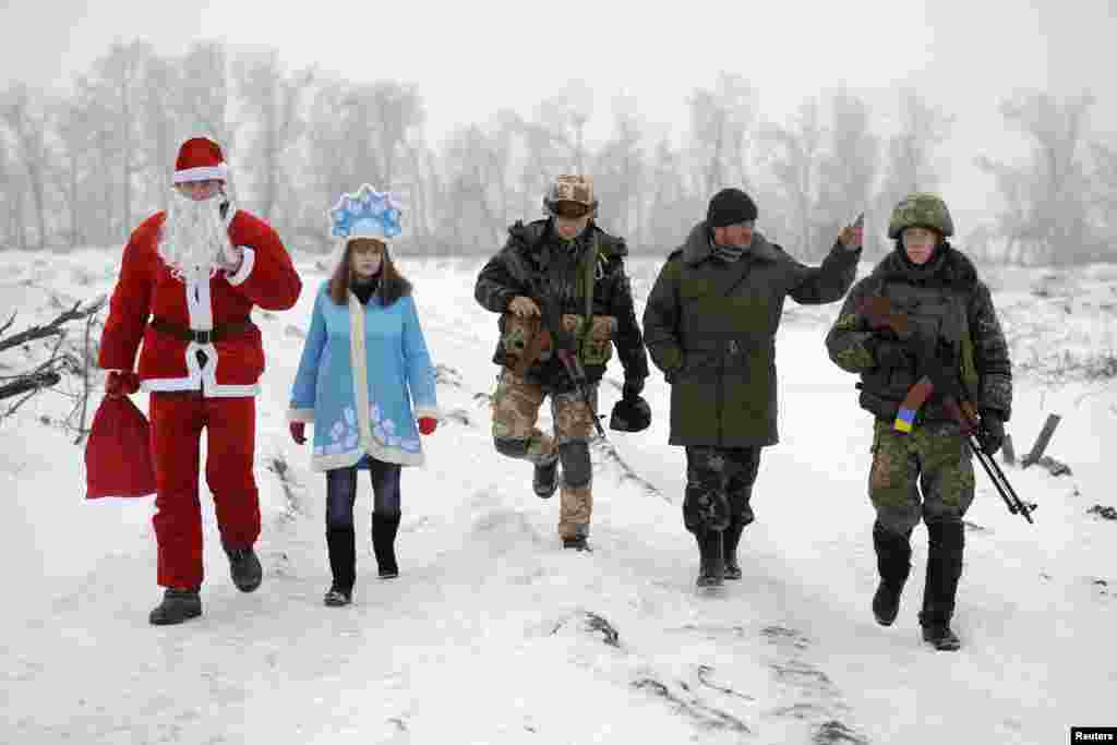 Local residents dressed as Father Frost and his granddaughter Snegurochka (Snow Maiden) walk with servicemen as they visit checkpoints of the Ukrainian Army and self-defense units to help welcome in the near year near Lysychansk in the Luhansk region. (Reuters)