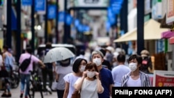 Disa persona me maska në rrugët e Japonisë.