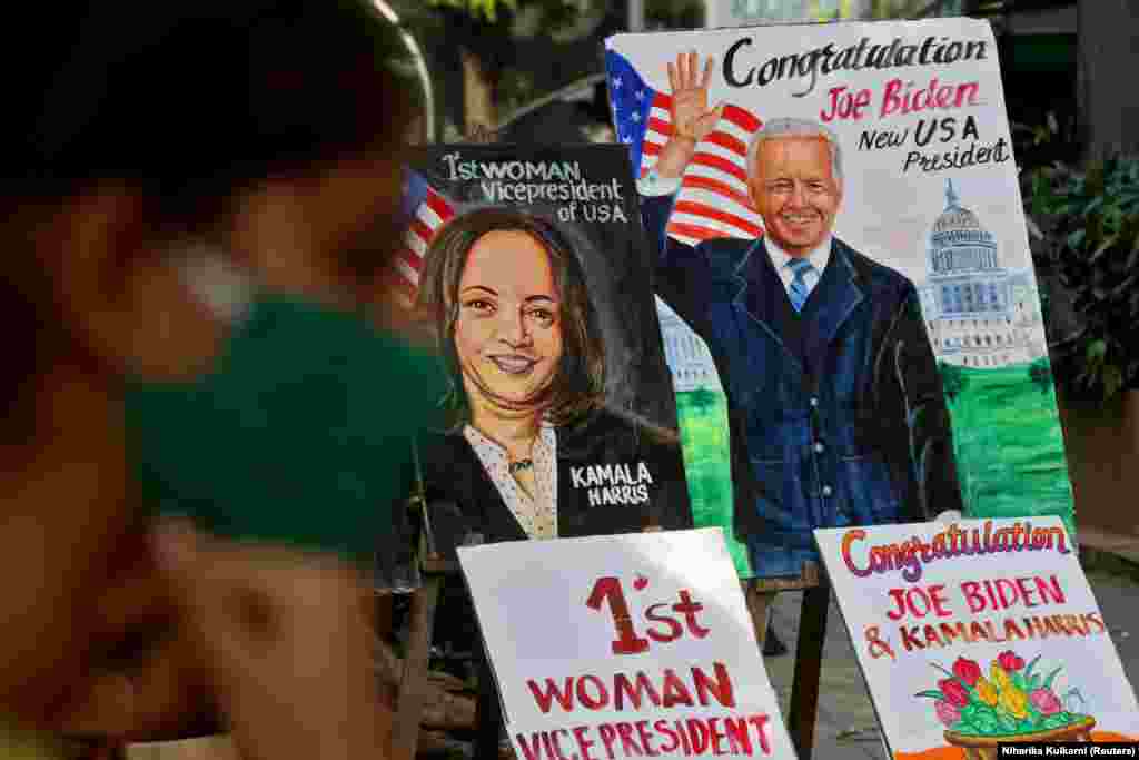 A girl sits next to paintings of U.S. President-elect Biden and Vice President-elect Harris on display alongside a road in Mumbai, India, on November 8, 2020. In addition to being the first African-American vice president, Harris was also the first Asian-American vice president.