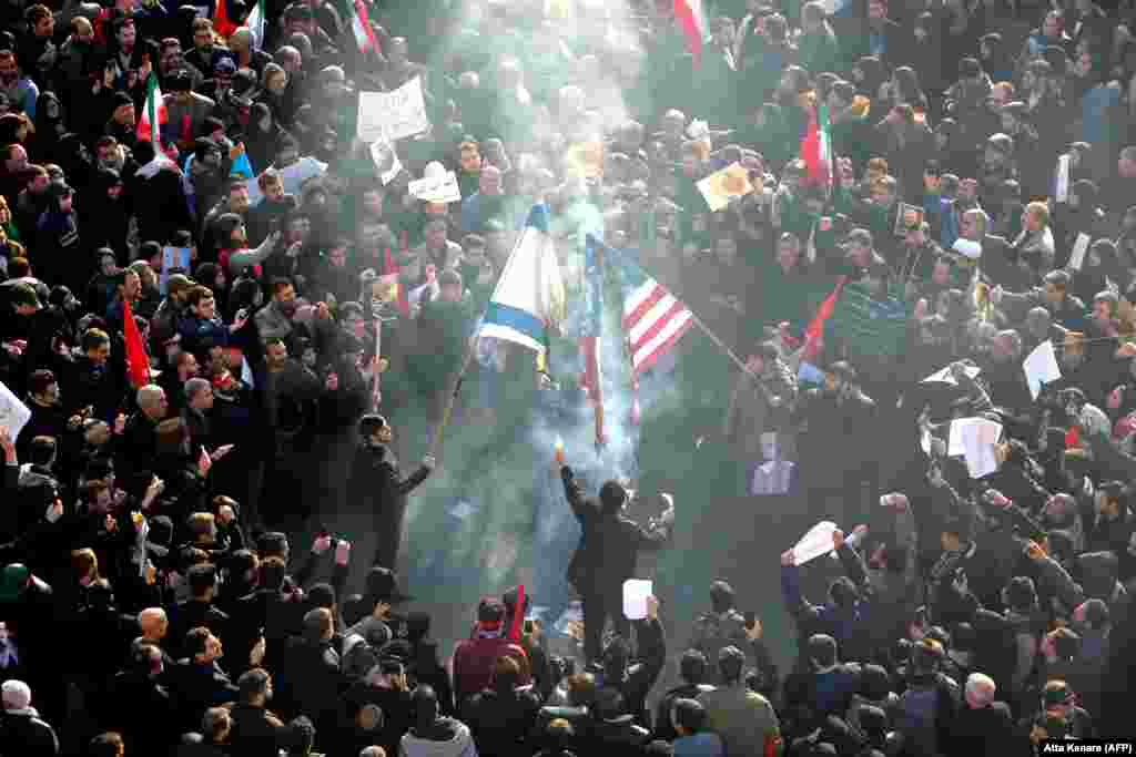 Participanții la funerarii dau foc steagurilor Statelor Unite și Israelului.