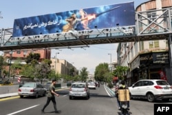Un banner care îl înfățișează pe erou mitic persan Arash trăgând o rachetă cu arcul, cu textul în limba persană „Nu voi abandona patria mea”, este atârnat pe un pod pietonal din centrul Teheranului, pe 15 aprilie 2024.