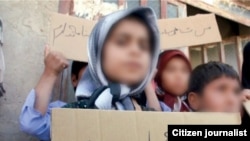 A child without citizenship In Iran holds a placard saying "I don't have an ID". Undated