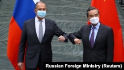 Russian Foreign Minister Sergei Lavrov (left) and his Chinese counterpart, Wang Yi, pose for a picture during a meeting in China on March 22.