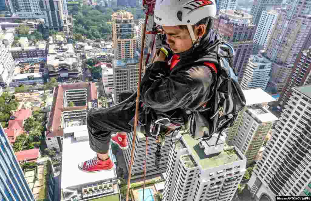 A worker scales a skyscraper to install Christmas and New Year&#39;s lights in Bangkok. (AFP/Mladen Antonov)