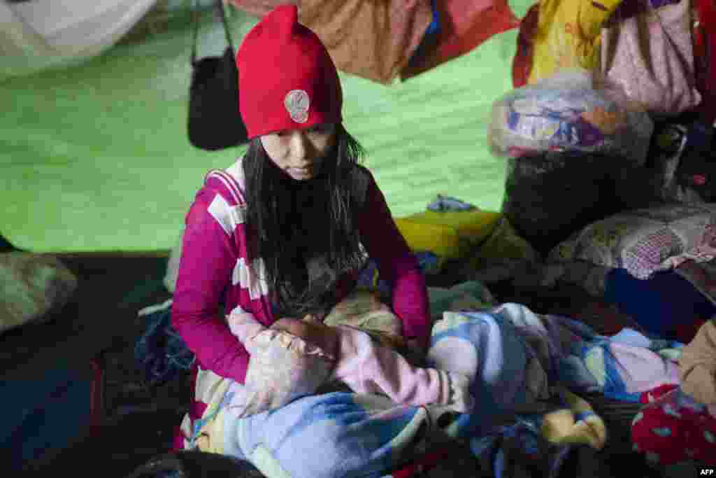 Internally displaced mother Seng Moon, fleeing renewed fighting between Burma&#39;s army and ethnic insurgents in the country&#39;s remote north, waits in a temporary shelter with her one-month-old daughter in Danai, Kachin state, on May 12. (AFP/Ye Aung Thu)