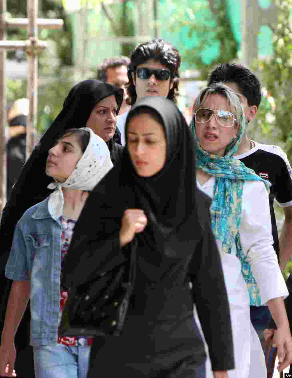 Iranian women in traditional and modern dress walk in Tehran. Some women say they dress conservatively in public but more daringly in their private lives.