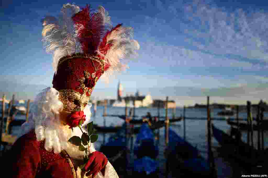 A reveler wearing a mask and a period costume smells a rose as he takes part in the Venice Carnival. (AFP/Alberto Pizzoli)