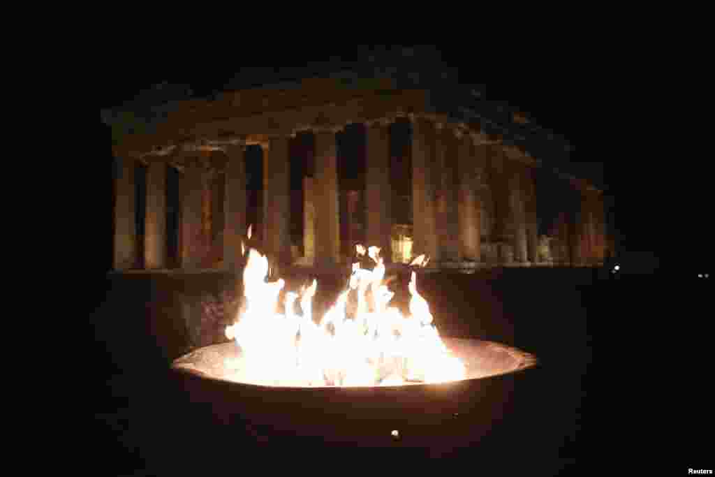 An Olympic flame is lit at an altar during the torch relay of the Sochi 2014 Winter Olympics in front of the Parthenon at the Acropolis hill in Athens. (Reuters/Yorgos Karahalis)