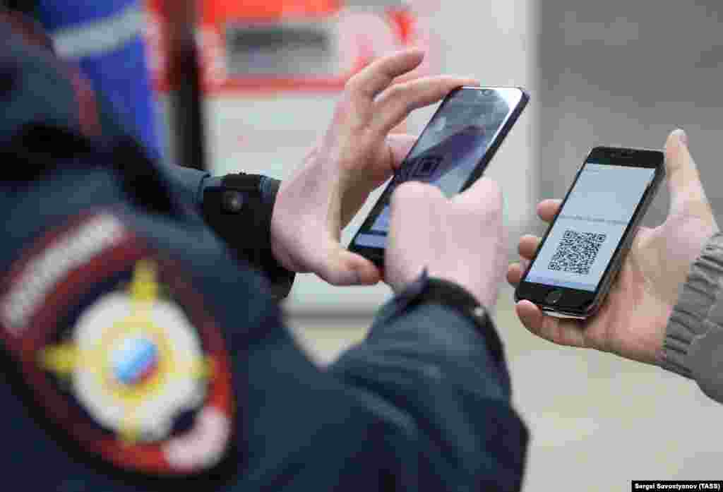 A police officer looks at a QR code on a commuter&#39;s smartphone during an ID check at Planernaya Station of the Moscow Underground (metro) during the pandemic of the novel coronavirus disease (COVID-19) on April 15 in Moscow, Russia. Under the digital permit system introduced by Moscow government, which became mandatory from 15 April, people need to apply for permits to travel on public transport or a vehicle around the city.&nbsp;
