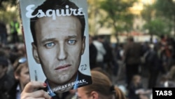 Активист оппозиции держит журнал с фотографией Алексея Навального.