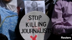 A Pakistani journalist holds a sign and a picture of Associated Press photographer Anja Niedringhaus,, who was killed on April 4, 2014, in Afghanistan, during a demonstration in Islamabad to condemn attacks against journalists.