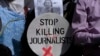 A Pakistani journalist holds a sign and a picture of Associated Press photographer Anja Niedringhaus,, who was killed on April 4, 2014, in Afghanistan, during a demonstration in Islamabad to condemn attacks against journalists.