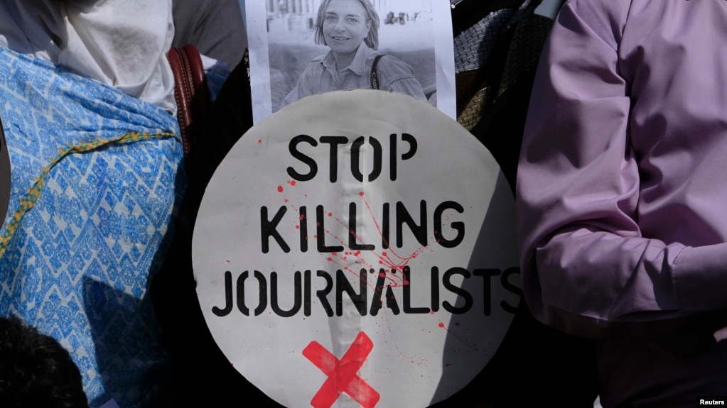 A Pakistani journalist holds a sign and a picture of Associated Press photographer Anja Niedringhaus,, who was killed on April 4, 2014, in Afghanistan, during a demonstration in Islamabad to condemn attacks against journalists.