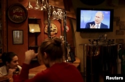 Patrons in a bar in Russia's Stavropol region pay no mind as Putin answers questions from the public on a TV overhead.