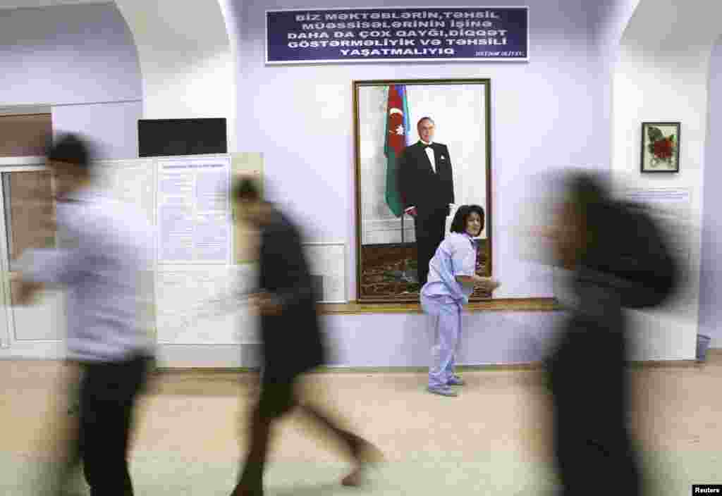 Azerbaijani election officials walk past a portrait of late President Heydar Aliyev at a polling station located inside a school building in Baku. (Reuters/David Mdzinarishvili)