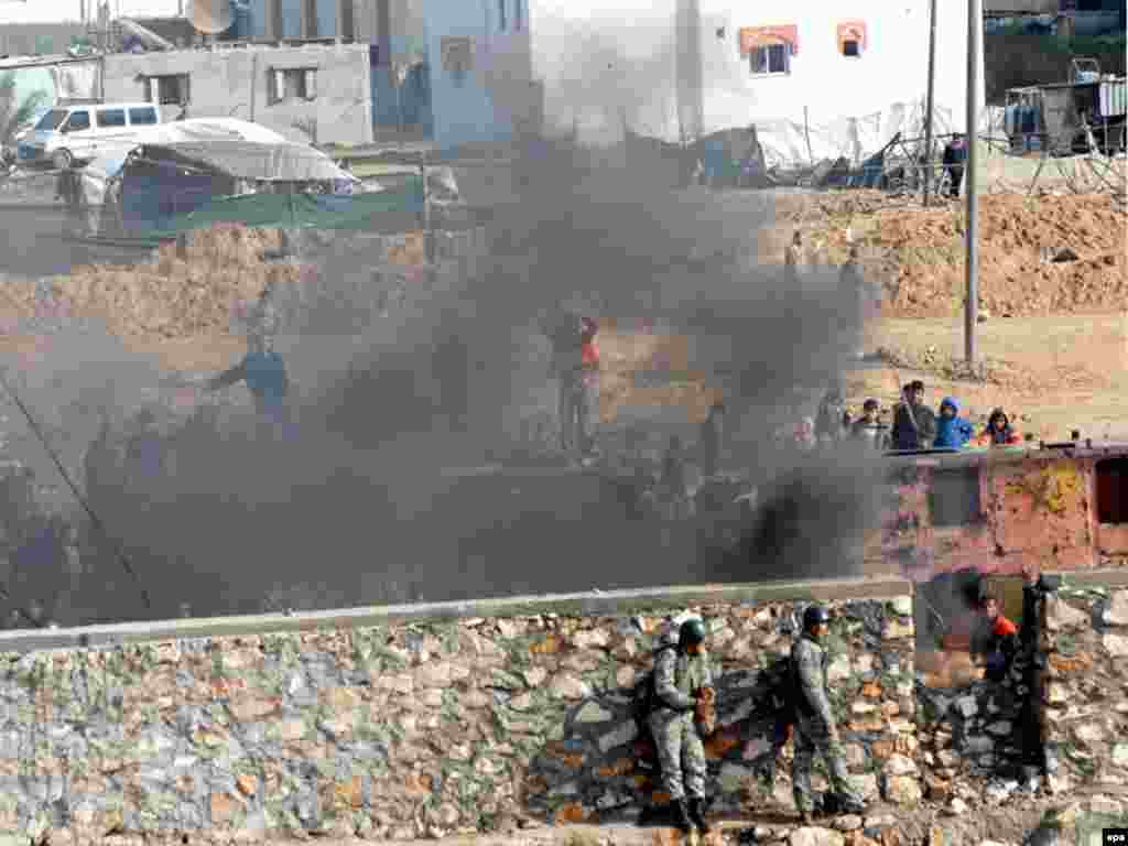 Египетские пограничники прячутся от за стеной от камней палестинцев на границе Египта и Газы. Как сообщают, один египетский пограничник был убит во время последующей перестрелки с палестинцами, 29 декабря 2008.
