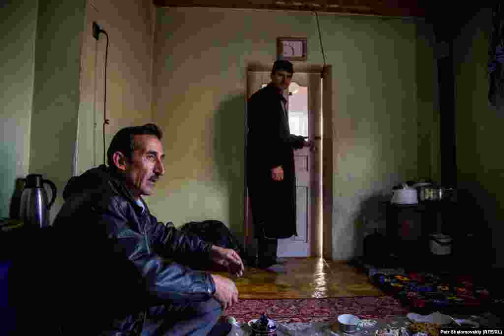 Nazar Boberov, the great-uncle of Umarali, and a relative have tea before visiting the child's grave in the village of Boboi Vali.