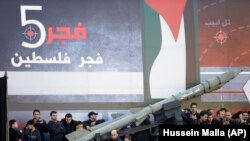 Shiite Muslim supporters of the Hezbollah, gather around a symbolic missile of Fajr 5 (Dawn 5), as they listen to the speech of Hezbollah leader Sheik Hassan Nasrallah during Ashoura Day, in the southern suburb of Beirut, Lebanon, Sunday Nov. 25, 2012.