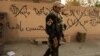 An Iraqi soldier walks past graffiti, which reads: "Islamic State will remain," in Bartilla, east of Mosul, on October 27. 