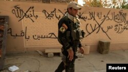 An Iraqi soldier walks past graffiti, which reads: "Islamic State will remain," in Bartilla, east of Mosul, on October 27. 