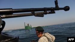 An Iranian Army soldier stands guard on a military speed boat during navy exercises in the Strait of Hormuz in December.