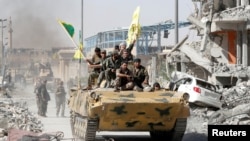 File photo - Syrian Democratic Forces (SDF) fighters ride atop of military vehicle as they celebrate victory in Raqqa, Syria, October 17, 2017.