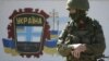 An armed man stands guard near a Ukrainian border guards base not far from the village of Perevalne, the site of a Ukrainian military base.