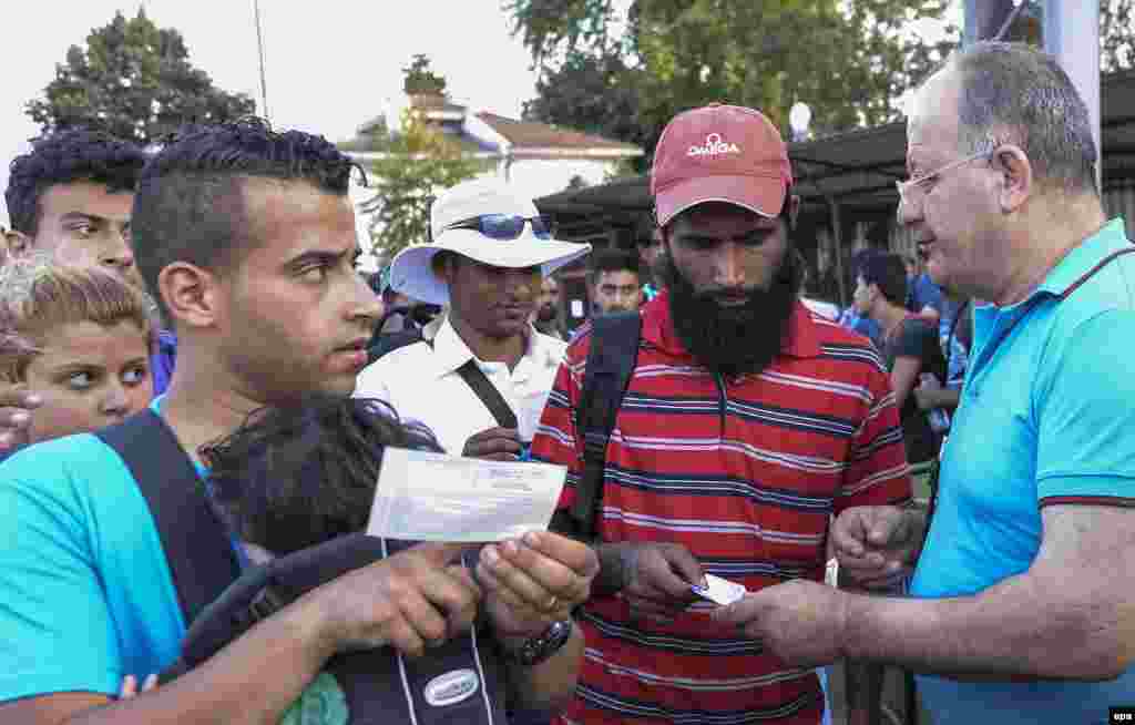 Bilet nəzarətçisi migrantların biletlərini yoxlayır. Gevgelija, Makedonia (epa/Georgi Licovski)