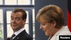 Russian President Dmitry Medvedev (left) looks toward German Chancellor Angela Merkel at a news conference in Hanover on July 19.