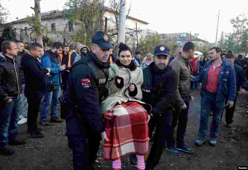 A woman being carried to safety in Thumane.