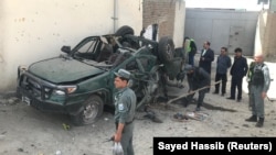 FILE; Afghan policemen inspect a damaged police vehicle after a suicide attack in Kabul.