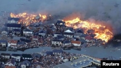 Будынкі, ахопленыя агнём, змывае цунамі. Наторы, паўночны усход Японіі. 11 сакавіка 2011 г. 