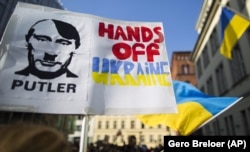 Activists holding placards depicting Russian President Vladimir Putin as Adolf Hitler demonstrate in front of the Ukrainian Embassy in Berlin.