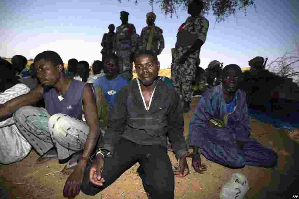 Malian soldiers guard handcuffed prisoners after they arrived by boat in Kadji on the Niger River on March 1. (AFP)