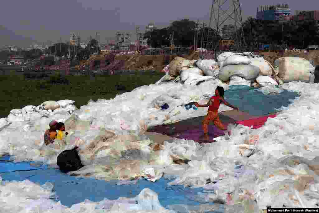 A girl plays with a toy gun at a plastics recycling yard in Dhaka, Bangladesh. (Reuters/Mohammad Ponir Hossain)