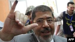 Muslim Brotherhood presidential candidate Mohammed Mursi shows the indelible ink stain on his little finger after voting at a polling station in Zagazig city on May 23.