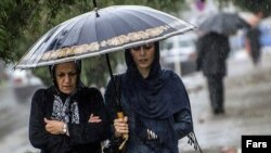 Two women try to keep dry in an autumn rainfall in Rasht, Iran.