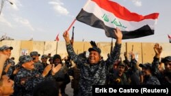 A member of the Iraqi Federal Police waves an Iraqi flag as he and his comrades celebrate victory against Islamic State militants in western Mosul on December 9.