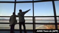 Посетители обзорной площадки на южнокорейской стороне у демилитаризованной зоны - рассматривают территорию Северной Кореи.