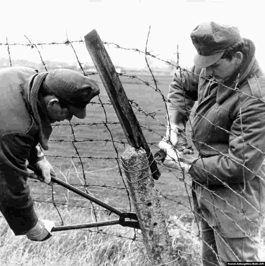 Венгерские пограничники демонтируют забор из колючей проволоки на австрийской границе, примерно в 50 километрах к востоку от Вены. Демонтаж пограничного ограждения в мае 1989 года стал первым шагом к открытию границы с Западной Европой