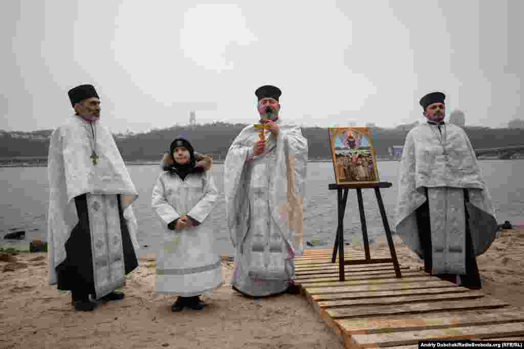 An Orthodox priest blesses the waters of the Dnieper River at the Peredmistna Slobidka public beach in the Ukrainian capital. This year&#39;s Epiphany swim was held in honor of Ukrainian military volunteers who served with the Aydar battalion is eastern Ukraine.