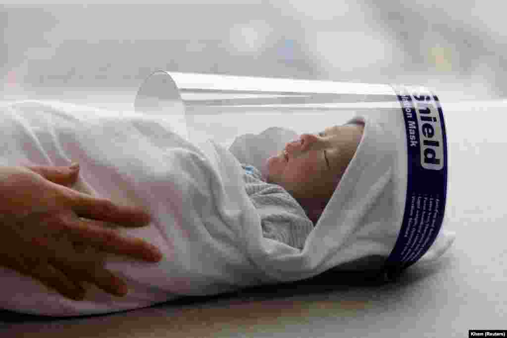 Новонароджене немовля в захисній масці перед від&#39;їздом додому з пологового будинку під час спалаху коронавірусу (COVID-19) в Ханої, В&#39;єтнам (REUTERS/Kham)